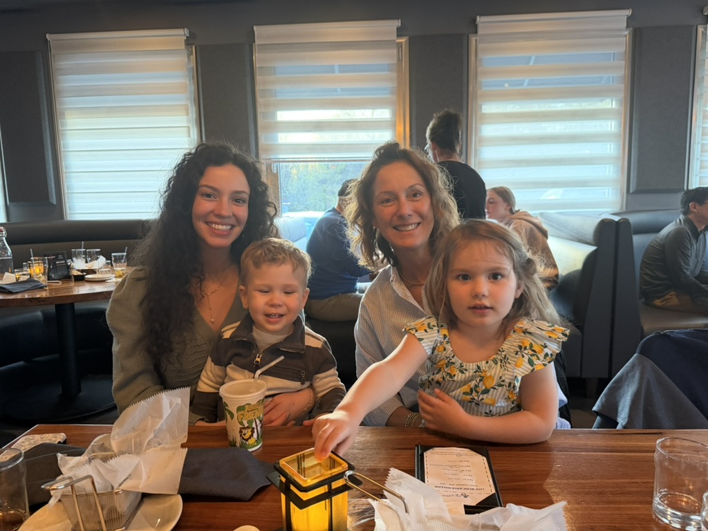Oma at the table with her family — holding her granddaughter, surrounded by warm light.